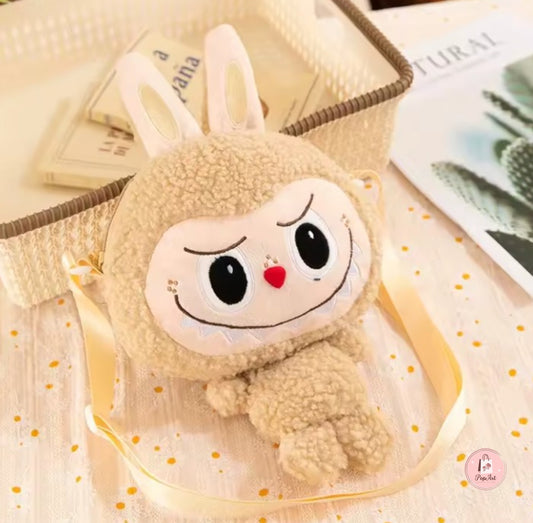 Sac Labubu beige en forme de peluche avec bandoulière ajustable, posé dans un décor épuré.
