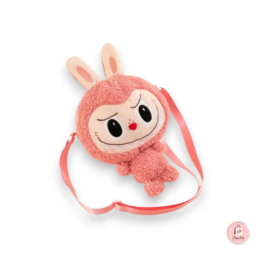 Sac Labubu rose en forme de peluche avec bandoulière, posé sur une surface pastel kawaii.